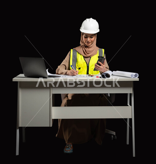 مواكبة التطورات و التكنولوجيا الحديثة في المملكة العربية السعودية, متابعة المشاريع الإنشائية عبر الهاتف المحمول, بورتريه لمهندسة عربية خليجية سعودية محجبة ترتدي سترة الحماية تقوم بالتعديل على مخطط الإعمار عن طريق  بعض التطبيقات والمواقع الهندسية, خلفية سوداء