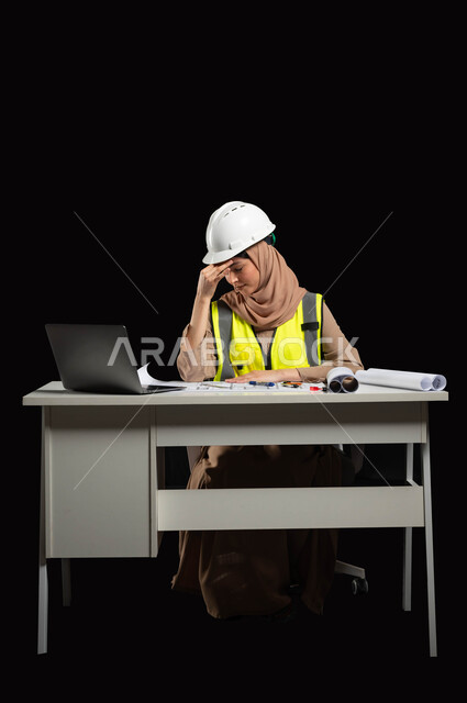 عمل المرأة السعودية في مختلف القطاعات, إدارة المشاريع الهندسية، بورتريه لمهندسة عربية خليجية سعودية محجبة ترتدي الخوذة وسترة الحماية تضع يدها على رأسها بإيماءات تدل على التعب والإرهاق, الاجتهاد في العمل، الإحساس بالمشقّة والحاجة للراحة، خلفية سوداء