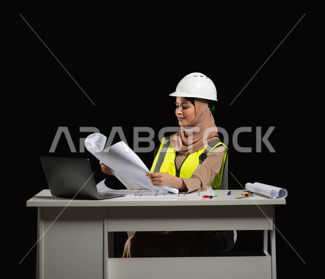 Scrutinizing engineering plans for their implementation, a close-up portrait of a Saudi Arabian Gulf engineer wearing a protection jacket and helmet, following up on the work and project plans, black background, sensitive content, sensitive use