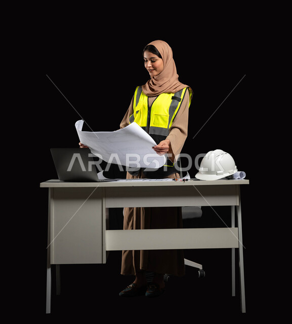 الإشراف على المخططات والتصاميم الهندسية, دور الهندسة الإنشائية في تطور المجتمع السعودي,  بورتريه مقرب لمهندسة عربية خليجية سعودية محجبة ترتدي سترة الحماية والخوذة تنظر إلى مخطط الإعمار بإيماءات الفخر والفرح, مهن ووظائف نسائية, خلفية سوداء
