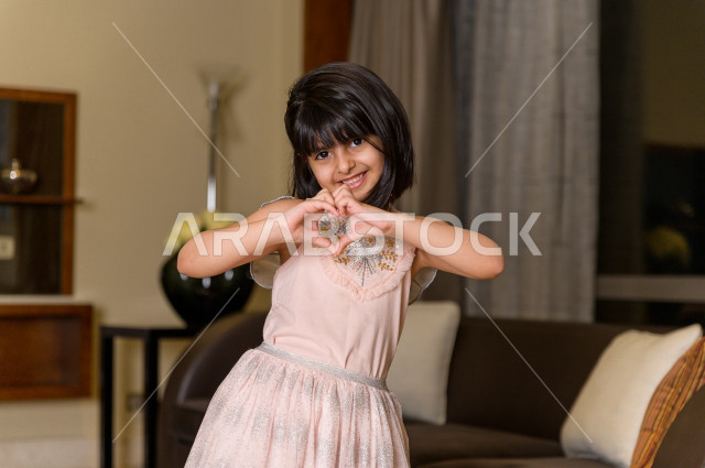 A Saudi girl wears a pink dress expressing love and happiness. A smiling beautiful Arab girl prepares for a souvenir photo, travel and tourism.