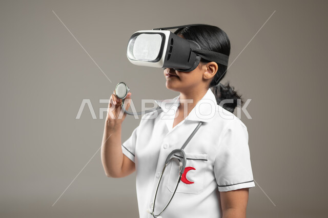 Integrating modern technology in the medical field, measuring the number of heartbeats, determining the future profession from a young age, a close-up portrait of a Saudi Gulf Arab girl wearing a nurse’s uniform, standing straight and wearing virtual world glasses, gray background, sensitive content, sensitive use