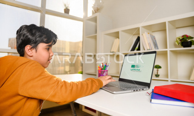 تلميذ سعودي خليجي يدرس في المنزل باستخدام جهاز التابلت ، يتابع حصص الاونلاين عن طريق الحاسوب المحمول ، الدراسة من خلال منصة تعليمية للتعلم عن بعد ، التعلم عن بعد ، مفهوم التعليم عبر الانترنت ، كورونا ، العزلة الذاتية .