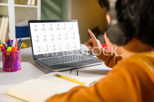 تلميذ سعودي خليجي يدرس في المنزل باستخدام جهاز التابلت ، يتابع حصص الاونلاين عن طريق الحاسوب المحمول ، الدراسة من خلال منصة تعليمية للتعلم عن بعد ، التعلم عن بعد ، مفهوم التعليم عبر الانترنت ، كورونا ، العزلة الذاتية .