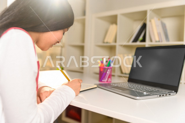 تلميذة سعودية خليجية تدرس في المنزل وتستخدم الحاسوب المحمول  ،الدراسة من خلال منصة تعليمية للتعلم عن بعد ، تأدية الواجبات المدرسية ، التعلم عن بعد ، مفهوم التعليم عبر الانترنت ، التعليم المنزلي ، العزلة الذاتية .