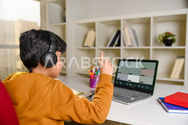 تلميذ سعودي خليجي يدرس في المنزل باستخدام جهاز التابلت ، يتابع حصص الاونلاين عن طريق الحاسوب المحمول ، الدراسة من خلال منصة تعليمية للتعلم عن بعد ، التعلم عن بعد ، مفهوم التعليم عبر الانترنت ، كورونا ، العزلة الذاتية .