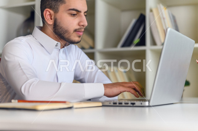 شاب سعودي خليجي يدرس في المنزل باستخدام جهاز التابلت، يتابع حصص الاونلاين ، التعلم عن بعد ، مفهوم التعليم عبر الانترنت ،الدراسة من خلال منصة تعليمية للتعلم عن بعد  ، العزلة الذاتية .