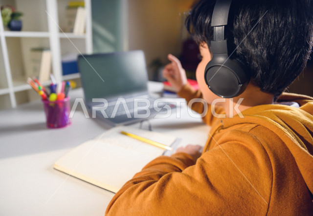 تلميذ سعودي خليجي يدرس في المنزل باستخدام جهاز التابلت ، يتابع حصص الاونلاين عن طريق الحاسوب المحمول ، الدراسة من خلال منصة تعليمية للتعلم عن بعد ، التعلم عن بعد ، مفهوم التعليم عبر الانترنت ، كورونا ، العزلة الذاتية .