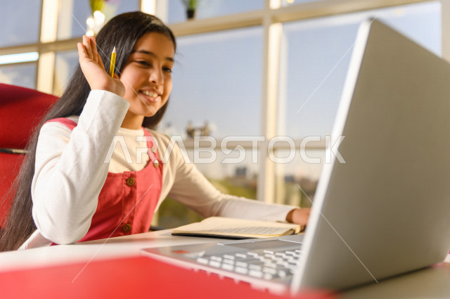 تلميذة سعودية خليجية تدرس في المنزل وتستخدم الحاسوب المحمول ،الدراسة من خلال منصة تعليمية للتعلم عن بعد ، تأدية الواجبات المدرسية ،  التعلم عن بعد ، مفهوم التعليم عبر الانترنت ، التعليم المنزلي ، العزلة الذاتية .