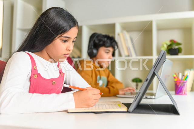 اخ و اخت  طالبان سعوديان خليجيان يدرسان في المنزل باستعانة الأجهزة التقنية ،الدراسة من خلال منصة تعليمية للتعلم عن بعد ، تأدية الواجبات المدرسية ،  التعلم عن بعد ، مفهوم التعليم عبر الانترنت ، التعليم المنزلي ، العزلة الذاتية .