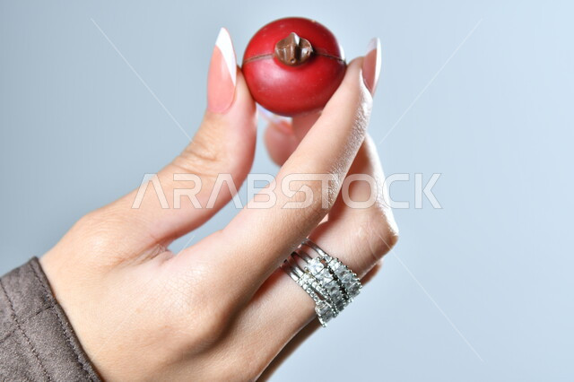 الأشكال الفنية المختلفة لحبات الشوكولاته الفاخرة، تقديم الحلويات في الأعياد والمناسبات، صورة مقربة ليد امرأة عربية تمسك بقطعة من الشوكولا، خلفية رمادية