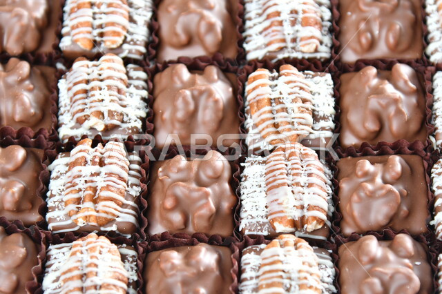 كرم الضيافة العربية، حلوى العيد اللذيذة، صورة مقربة لمجموعة من حبات الشوكولاته الفاخرة بأشكال فنية مختلفة، تقديم الحلويات والسكريات في الأعياد والمناسبات، خلفيه بيضاء