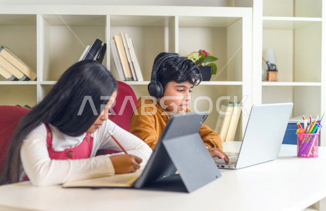 اخ و اخت  طالبان سعوديان خليجيان يدرسان في المنزل باستعانة الأجهزة التقنية ،الدراسة من خلال منصة تعليمية للتعلم عن بعد ، تأدية الواجبات المدرسية ،  التعلم عن بعد ، مفهوم التعليم عبر الانترنت ، التعليم المنزلي ، العزلة الذاتية .