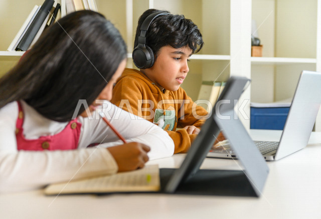اخ و اخت  طالبان سعوديان خليجيان يدرسان في المنزل باستعانة الأجهزة التقنية ،الدراسة من خلال منصة تعليمية للتعلم عن بعد ، تأدية الواجبات المدرسية ،  التعلم عن بعد ، مفهوم التعليم عبر الانترنت ، التعليم المنزلي ، العزلة الذاتية .