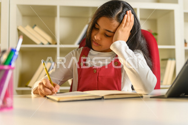 تلميذة سعودية خليجية تقوم بحل الواجبات في المنزل ،الدراسة من خلال منصة تعليمية للتعلم عن بعد ، تأدية الواجبات المدرسية ، ايماءات وجه تدل على التفكير، التعلم عن بعد ، مفهوم التعليم عبر الانترنت ، التعليم المنزلي ، العزلة الذاتية .