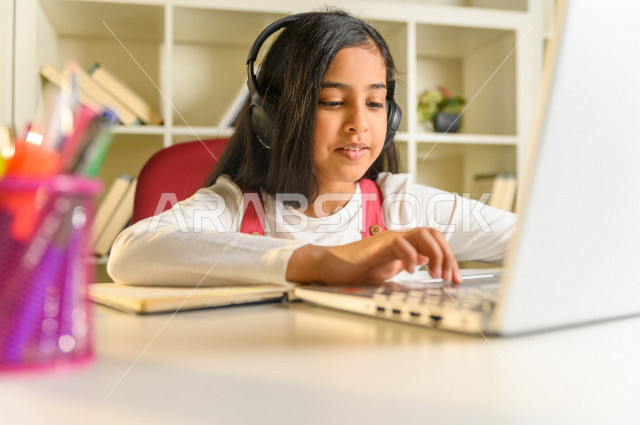 تلميذة سعودية خليجية تقوم بحل الواجبات في المنزل ،الدراسة من خلال منصة تعليمية للتعلم عن بعد ، تأدية الواجبات المدرسية ، ايماءات وجه تدل على التفكير، التعلم عن بعد ، مفهوم التعليم عبر الانترنت ، التعليم المنزلي ، العزلة الذاتية .