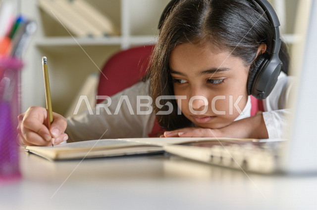 تلميذة سعودية خليجية تقوم بحل الواجبات في المنزل ،الدراسة من خلال منصة تعليمية للتعلم عن بعد ، تأدية الواجبات المدرسية ، ايماءات وجه تدل على التفكير، التعلم عن بعد ، مفهوم التعليم عبر الانترنت ، التعليم المنزلي ، العزلة الذاتية .