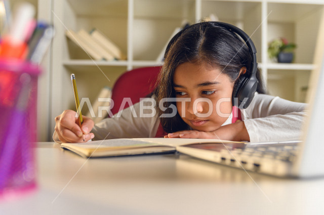 تلميذة سعودية خليجية تقوم بحل الواجبات في المنزل ،الدراسة من خلال منصة تعليمية للتعلم عن بعد ، تأدية الواجبات المدرسية ، ايماءات وجه تدل على التفكير، التعلم عن بعد ، مفهوم التعليم عبر الانترنت ، التعليم المنزلي ، العزلة الذاتية .