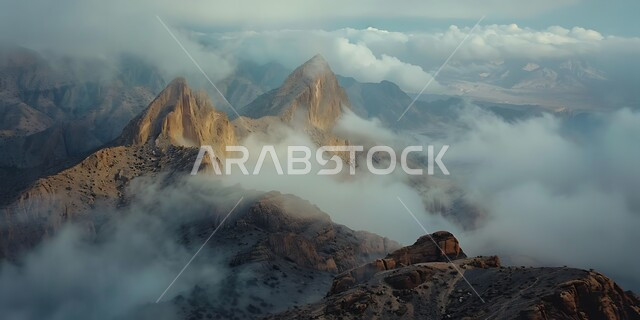 الوديان والقمم الصخرية في البراري، منظر الغيوم والسحب البيضاء في السماء تخترق سلسلة الجبال والتكوينات والتشكلات الصخرية في المناطق الصحراوية، اماكن سياحية مشهورة في المملكة العربية السعودية