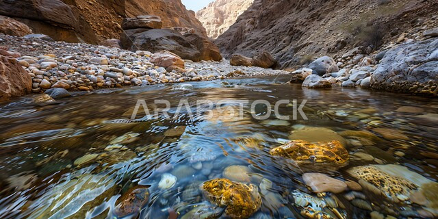 جريان المياه الصافية في وادي بين سلسلة الجبال والتكوينات والتشكلات الصخرية في المناطق الصحراوية، الوديان والقمم الصخرية في البراري، اماكن سياحية مشهورة في المملكة العربية السعودية