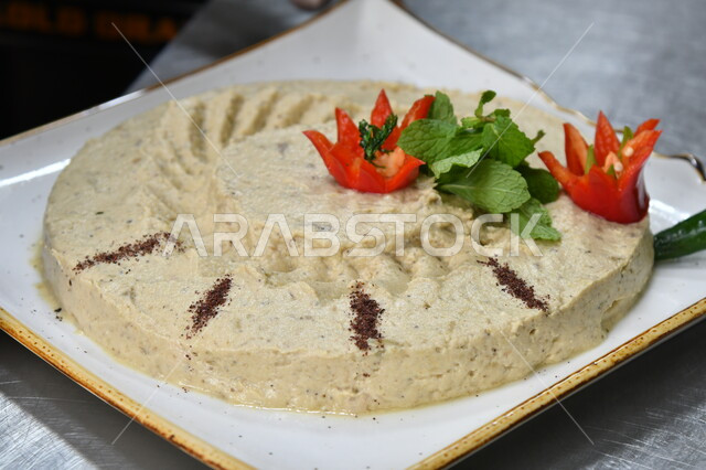 الأساليب الفنية لتقديم الطعام، المقبلات النباتية الباردة اللذيذة، صورة مقربة لطبق من الحمص اللذيذ المزين بالتوابل والخضراوات، مأكولات وأطباق شعبية تقليدية، وصفات شرقية عربية سعودية