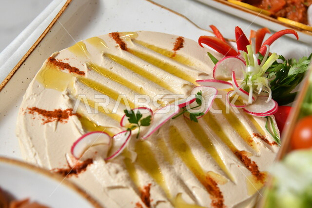 المقبلات النباتية الباردة اللذيذة، صورة مقربة لطبق من الحمص اللذيذ المزين بالتوابل والخضراوات، مأكولات وأطباق شعبية تقليدية، وصفات طعام شرقية عربية سعودية، تزيين الطعام بأسلوب فني