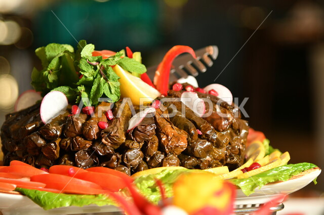 طبق محشي ورق العنب اللذيذ المزين بالخضراوات الطازجة وحبات الرمان الشهية، مطاعم ومطابخ المملكة العربية السعودية، المأكولات والوجبات العربية الشرقية، اطباق المقبلات وفاتحات الشهية اللذيذة