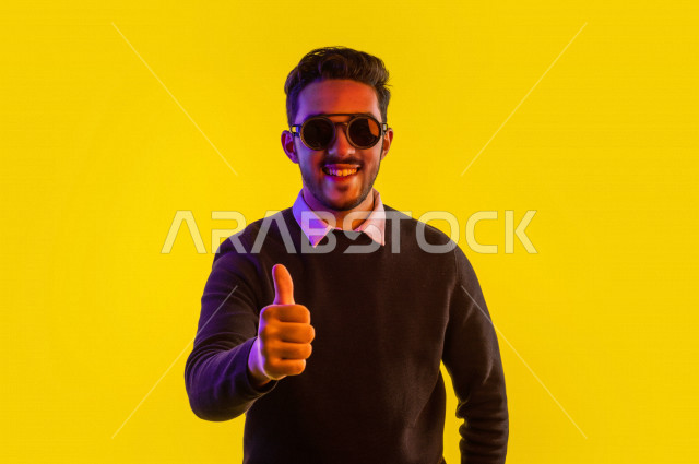 بورتريه رجل سعودي خليجي سعيد ، يرتدي نظارة شمسية  ، ايماءات وجه و يدين مختلفة تدل على السعادة و الفرحة ، الحيوية و الترفيه  ،  خلفية ملونة