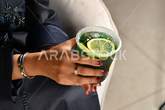 مشروبات صيفية باردة، صورة مقربة لأيدي فتاة عربية خليجية سعودية تمسك كأس من عصير النعنع والليمون، مرطبات وعصائر منعشة وصحية، الاهتمام بالمظهر الخارجي