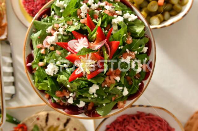 Delicious Arabic appetizer dishes, a vertical photo from above of a plate of fresh vegetable salad decorated with cheese, delicious oriental food, the arts of food presentation in Saudi kitchens and restaurants