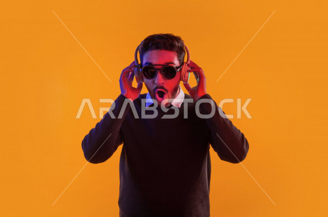 بورتريه رجل سعودي خليجي سعيد ، يضع سماعة رأس ، ايماءات وجه و يدين تدل على السعادة و الاستمتاع ، موهبة الغناء ، خلفية ملونة