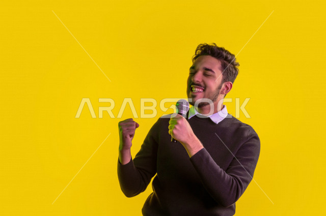 بورتريه رجل سعودي خليجي سعيد ،  يحمل الميكروفون و يقوم بالغناء  ، ايماءات وجه و يدين تدل على السعادة و الاستمتاع ، موهبة الغناء ، خلفية ملونة