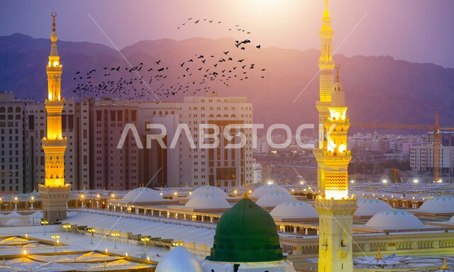 The green dome and illuminated minarets in Al-Rawdah Al-Sharifa at sunset, an overhead aerial photo of the Prophet’s Mosque in Medina, Saudi Arabia, sacred Islamic religious monuments and places
