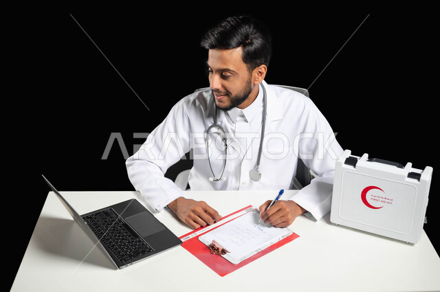 تقديم الخدمات الطبية للمرضى و متابعة حالاتهم عبر الحاسوب المحمول, استخدام حقيبة الاسعافات الاوليه، بورتريه لطبيب عربي خليجي سعودي مبتسم يرتدي المعطف و السماعة الطبية يقوم بكتابة وتدوين التقارير والحالات الصحيه, خلفية سوداء, محتوى حساس, استخدام حساس