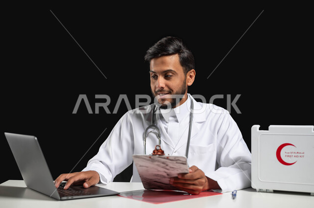 متابعة المرضى عبر التطبيقات و التقنيات الحديثة و تقديم الخدمات الطبية, دمج العمل مع التكنولوجيا, بورتريه لطبيب عربي خليجي سعودي يرتدي المعطف الأبيض وسماعة الأذن يقوم بمتابعة الحالات المرضية على جهاز الحاسوب، خلفية سوداء, محتوى حساس, استخدام حساس