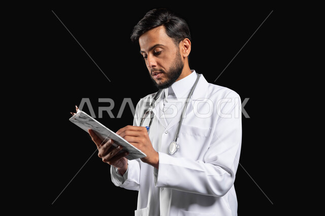 تدوين الحالات المرضية ومتابعه المرضى، الاهتمام بالمرضى وتسجيل الملاحظات الطبيه، بورتريه طبيب عربي خليجي سعودي يرتدي المعطف و السماعة الطبية يقوم بكتابة تقرير طبي، خلفية سوداء, محتوى حساس, استخدام حساس