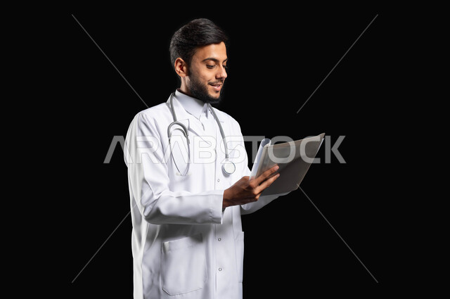 Recording medical notes and taking care of patients, recording and following up on medical cases, close-up portrait of a Saudi Gulf Arab doctor wearing a coat and stethoscope writing a medical report, black background, sensitive content, sensitive use
