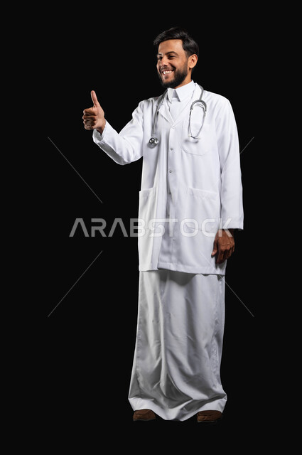الرضا عن الخدمات الطبيه والرعايه الصحيه, بورتريه مقرب لطبيب عربي خليجي سعودي يرفع اصبع الابهام بإيماءات الاعجاب والرضى بتحقيق أمر معين، صورة الجسم بالطول الكامل، خلفية سوداء، محتوى حساس، استخدام حساس