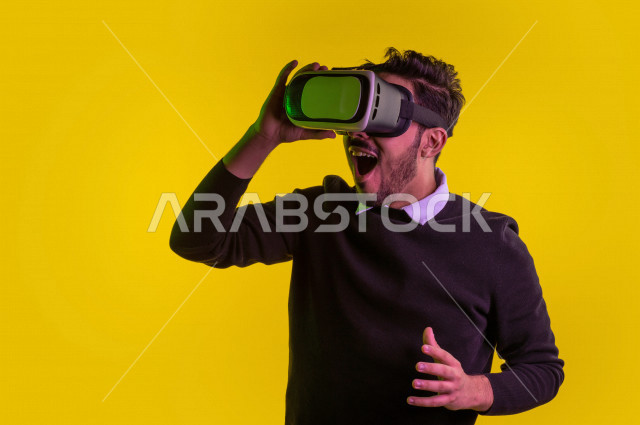 بورتريه رجل سعودي خليجي سعيد ،يضع جهازVR Box، ايماءات وجه و يدين تدل على السعادة و الاستمتاع ، استخدام تقنية ثلاثية الابعاد ، خلفية ملونة