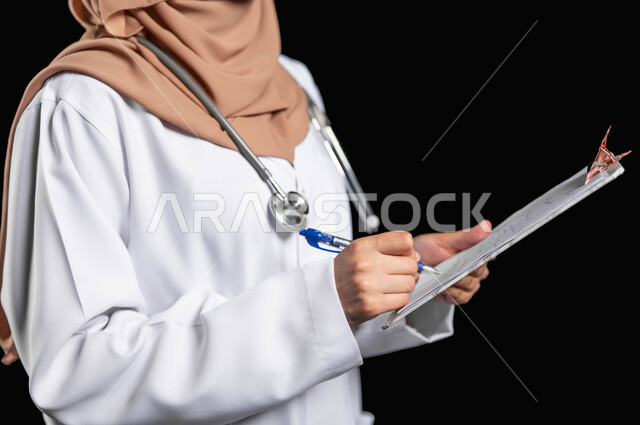 العمل في القطاع الصحي، كتابة الوصفات العلاجية والتقارير الصحيه، بورتريه مقرب لطبيبة عربية خليجية سعودية محجبة ترتدي المعطف مع السماعه الطبيه تقوم بتسجيل معلومات المرضى, خلفيه سوداء، محتوى حساس، استخدام حساس