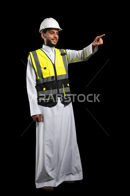 The concept of engineering and architectural construction, looking with smiling gestures, a close-up portrait of a Saudi Arabian Gulf engineer wearing traditional clothing and work clothes, pointing with his index finger in a specific direction, full-length body image, black background, sensitive content, sensitive use