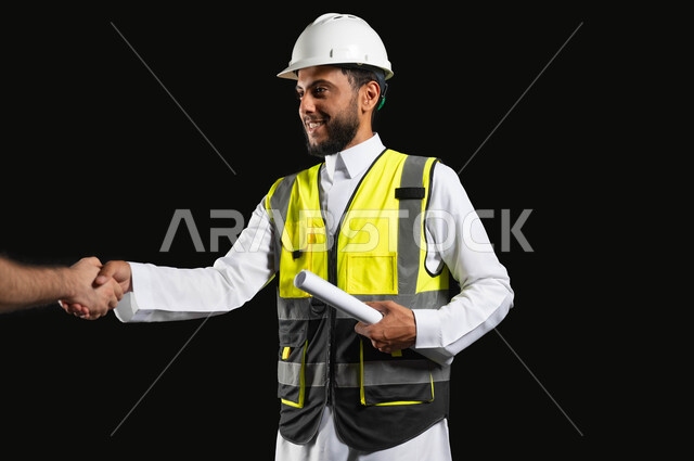 مهن ووظائف هندسية, اهمية التواصل مع العملاء في خدمة العمل، بورتريه لمهندس عربي خليجي سعودي يرتدي الزي التقليدي مع سترة الحماية والخوذة يحمل بيده مخططات المشروع، خلفية سوداء,محتوى حساس، استخدام حساس