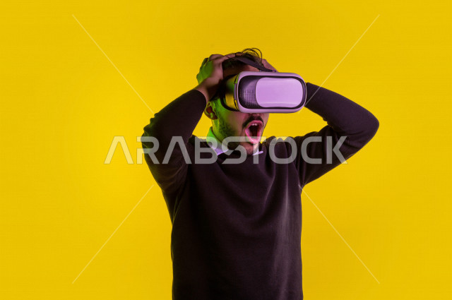 بورتريه رجل سعودي خليجي سعيد ،يضع جهازVR Box، ايماءات وجه و يدين تدل على السعادة و الاستمتاع ، استخدام تقنية ثلاثية الابعاد ، خلفية ملونة