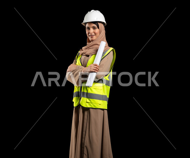 تقدم وتطور السعودية على يد أبناء الوطن, بورتريه لمهندسة عربية خليجية مبتسمة محجبة ترتدي الخوذة وسترة الحماية تمسك بيدها مخطط الإعمار, الهندسة والانشاءات المعمارية, الاهتمام بشؤون العمل,  خلفية سوداء, محتوى حساس, استخدام حساس