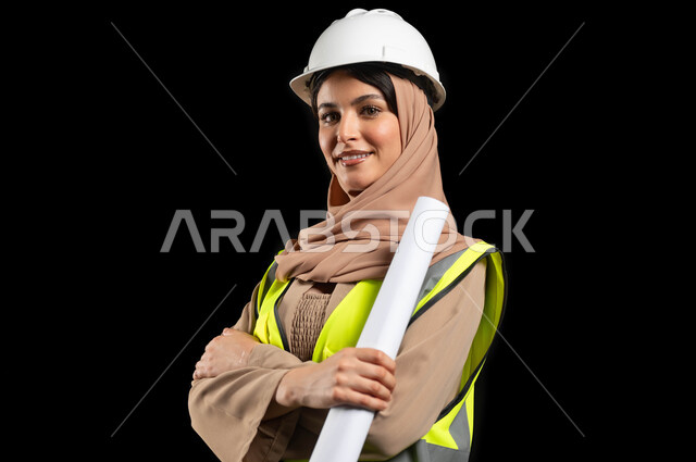 تطوير و بناء المملكة العربية السعودية على يد ابنائها, بورتريه مقرب لمهندسة عربية خليجية سعودية محجبة ترتدي خوذة الحماية و السترة تنظر الى الكاميرا مبتسمة، الإشراف على المشاريع الهندسية في موقع العمل, خلفية سوداء، استخدام حساس, محتوى حساس