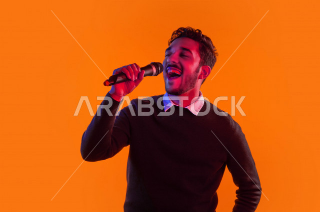 بورتريه رجل سعودي خليجي سعيد ،  يحمل الميكروفون و يقوم بالغناء  ، ايماءات وجه و يدين تدل على السعادة و الاستمتاع ، موهبة الغناء ، خلفية ملونة
