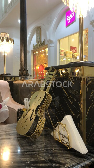 تقديم العروض والفنون الموسيقية الترفيهية في احدى المقاهي الفاخرة في مدينة الطائف، استخدام الآلات الوترية ، صورة مقربة لآلة الكمان على الطاولة في المطعم، التصاميم والديكورات الداخلية الراقية للكافيهات في المملكة العربية السعودية
