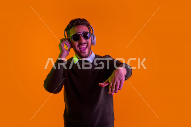 بورتريه رجل سعودي خليجي سعيد ، يضع سماعة رأس ، ايماءات وجه و يدين تدل على السعادة و الاستمتاع ، موهبة الغناء ، خلفية ملونة