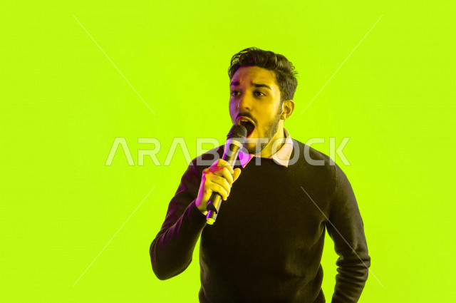 بورتريه رجل سعودي خليجي سعيد ،  يحمل الميكروفون و يقوم بالغناء  ، ايماءات وجه و يدين تدل على السعادة و الاستمتاع ، موهبة الغناء ، خلفية ملونة
