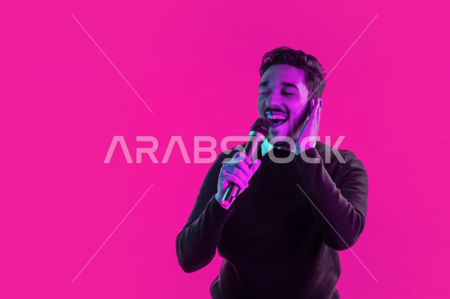 بورتريه رجل سعودي خليجي سعيد ،  يحمل الميكروفون و يقوم بالغناء  ، ايماءات وجه و يدين تدل على السعادة و الاستمتاع ، موهبة الغناء ، خلفية ملونة